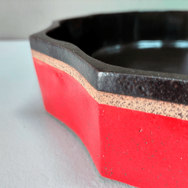 Centro de mesa em cerâmica alta temperatura. Peça feita em argila tabaco com esmaltes nas cores vermelho e café. Detalhe lateral.