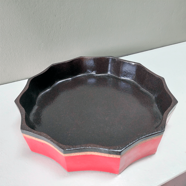 Centro de mesa em cerâmica alta temperatura. Peça feita em argila tabaco com esmaltes nas cores vermelho e café. Vista lateral.